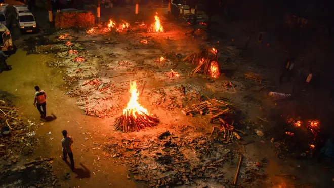 Funeral pyres of people who have died of Covid-19 burn during a mass cremation at a crematorium