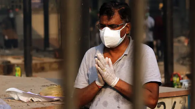 A family member performs the last rites of a person who died with coronavirus at a crematorium in New Delhi