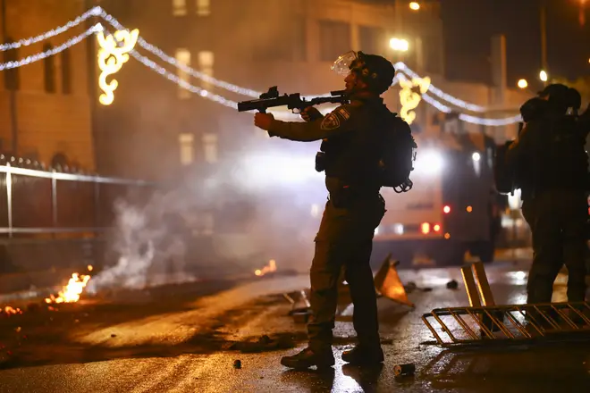 An Israeli police officer aims his rifle towards Palestinian demonstrators during clashes at Damascus Gate just outside Jerusalem's Old City.