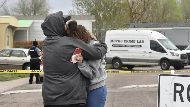 Freddy Marquez kisses the head of his wife, Nubia Marquez, near the scene of a fatal shooting which has been marked off with police tape