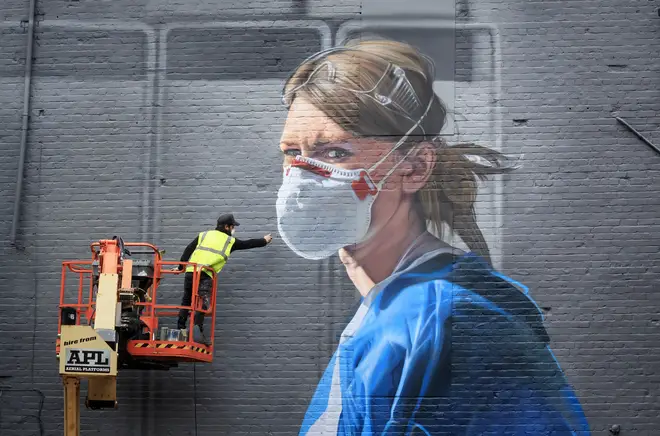 Artist Peter Barber working on a mural in Manchester city centre, depicting nurse Melanie Senior