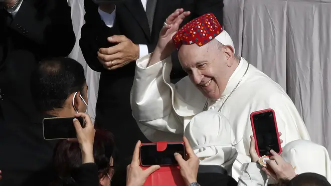 Pope Francis smiles after an attendee placed a hat on his head in the St Damaso Courtyard at the Vatican for his weekly general audience