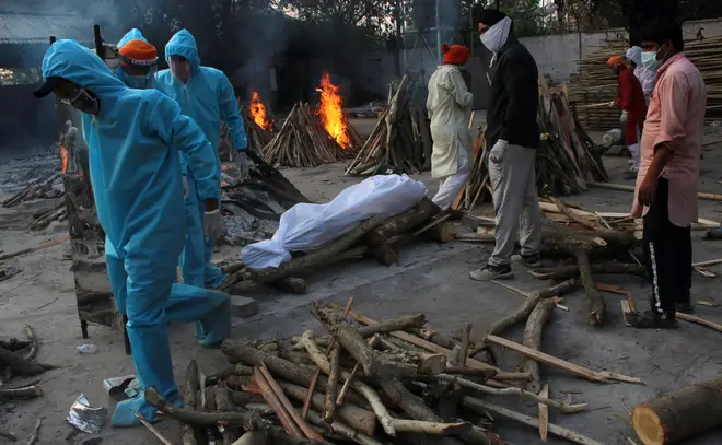 Family members in PPE prepare the body a Covid-19 victim for cremation in New Delhi, India