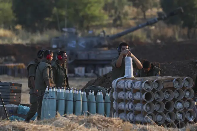 An Israeli soldier arms artillery shells next to an artillery unit at the Israeli-Gaza border