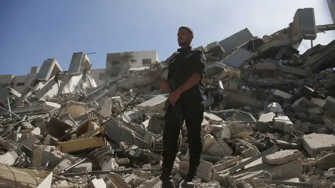 A policeman stands on rubble from a building housing AP office and other media in Gaza City that was destroyed after Israeli warplanes demolished it