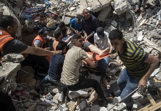 Palestinians rescue a survivor from under the rubble of a destroyed residential building following deadly Israeli airstrikes in Gaza on Sunday.