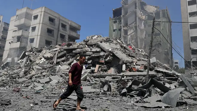 A man walks past the the rubble of the Yazegi residential building that was destroyed by an Israeli airstrike, in Gaza City