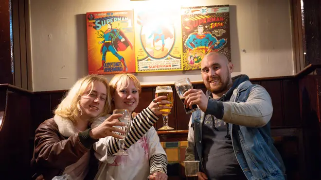 Punters raise a glass together inside a pub for the first time in months