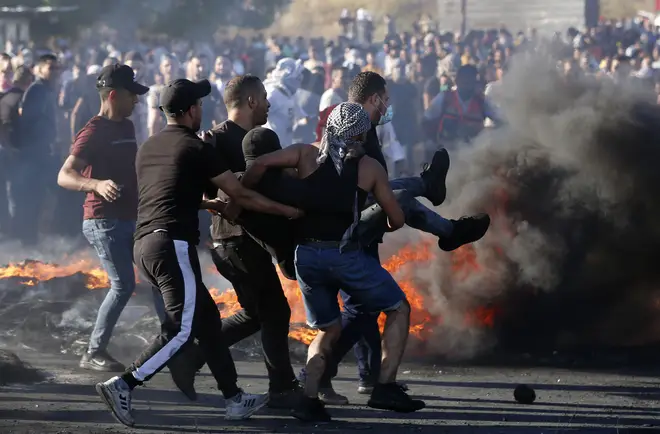 Protesters carry an injured man shot by Israeli soldiers during a protest against the ongoing Israeli airstrikes on the Gaza Strip at Huwwara checkpoint near the West Bank city of Nablus.