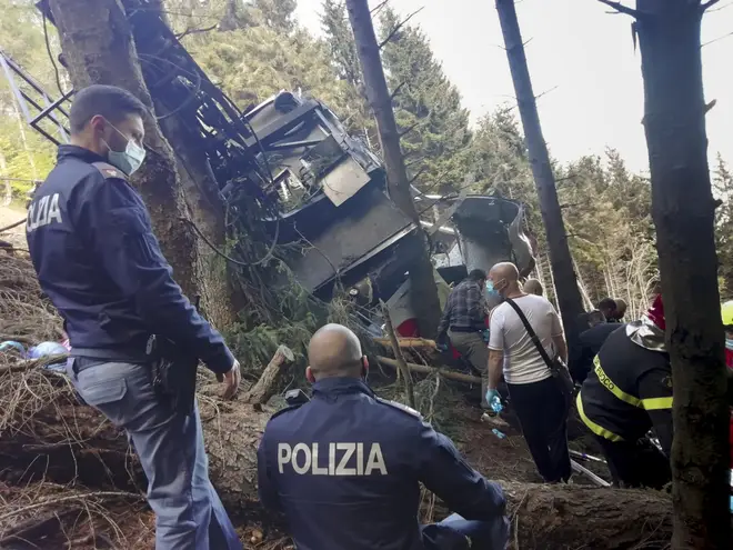 Rescuers work by the wreckage of a cable car