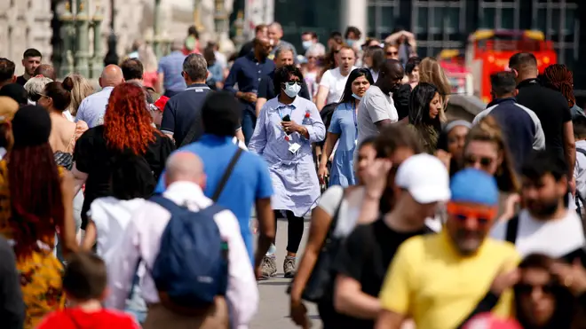 A woman wearing a face mask crosses a busy Westminster Bridge in London