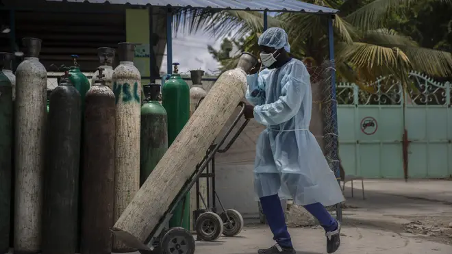 A hospital emplyee wearing protective gear as a precaution against the spread of the new coronavirus, transports oxygen tanks, in Port-au-Prince, Haiti (Joseph Odelyn/AP)