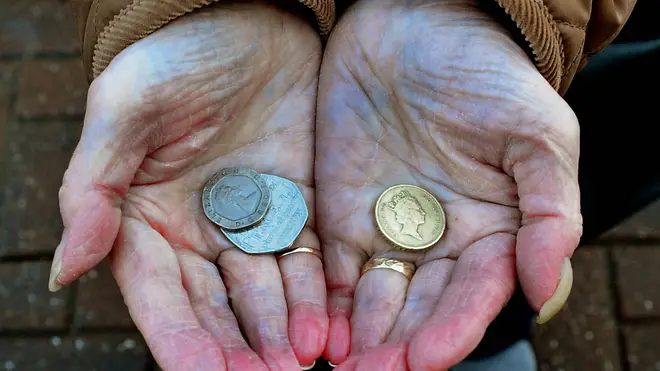 An elderly person holding a few coins