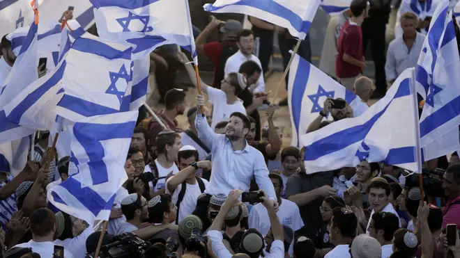 Israeli Knesset member Bezalel Smotrich, centre, waves his country's flag together with other Jewish ultra-nationalists during a march in East Jerusalem on Tuesday