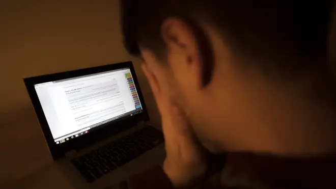 In a picture posed by a model, a man looks upset as he looks at a laptop computer