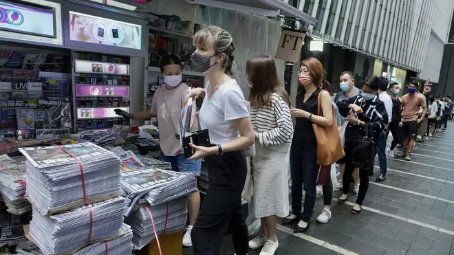 People queue up for last issue of Apple Daily at a newspaper booth at a downtown street in Hong Kong