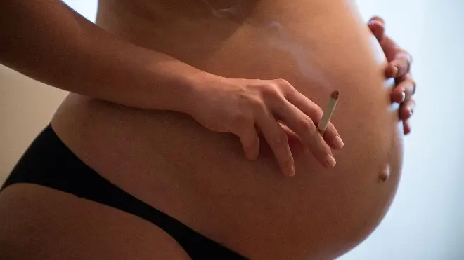 File photo showing a pregnant woman holding a burning cigarette in her hand