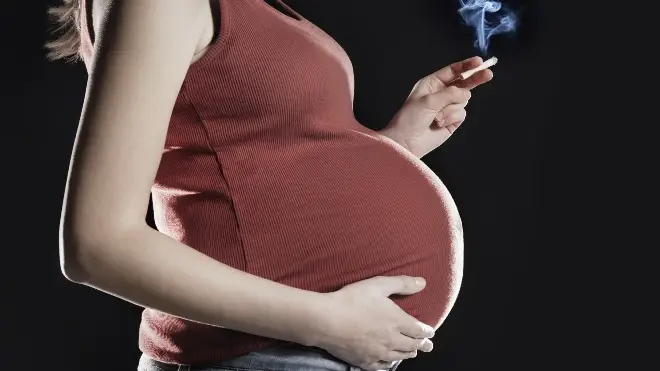 File photo showing a pregnant woman holding a cigarette