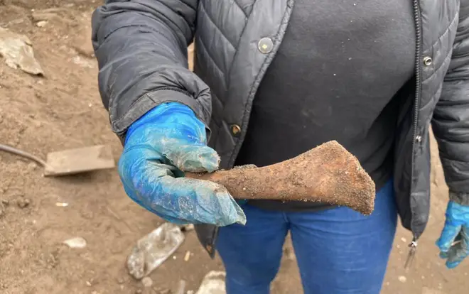 A volunteer shows an item that was found during the digging