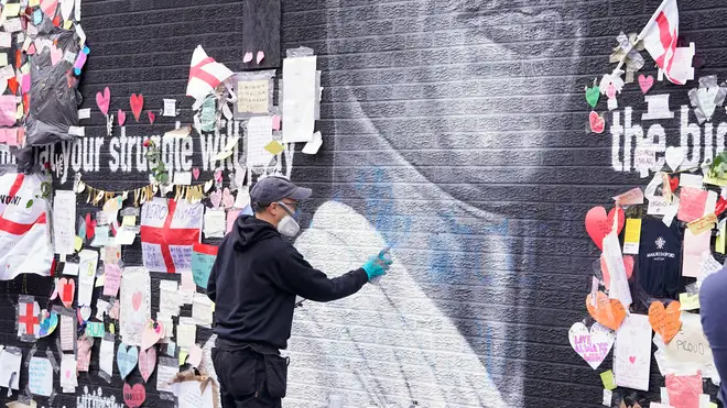 Street artist Akse P19 repairs the mural of Marcus Rashford