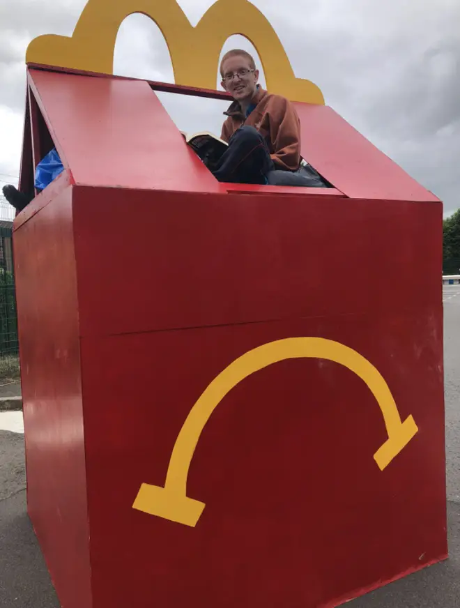 A protester sits in a replica of a Happy Meal box at the site