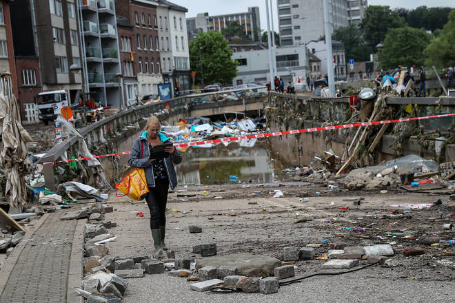 A woman walks past a tunnel filled with garbage after floods in Verviers, Belgium.
