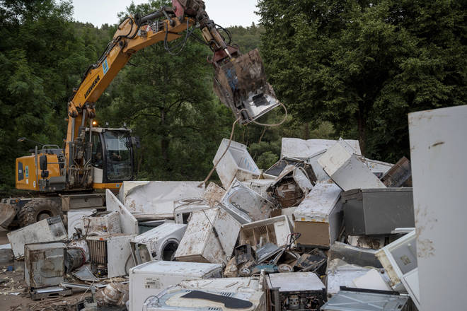 An excavator throws an electrical appliance onto the huge mountain of equipment damaged by the flood in Kordel, Germany.