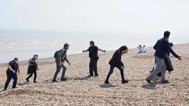 A group of people believed to be migrants being led up a beach in Kent