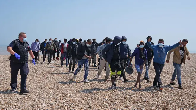 Migrants are escorted from the beach in Dungeness, Kent yesterday