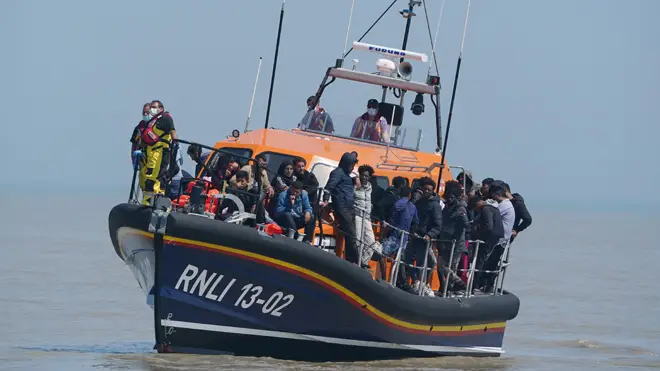 Migrants crossing from France come ashore aboard the local lifeboat at Dungeness in Kent