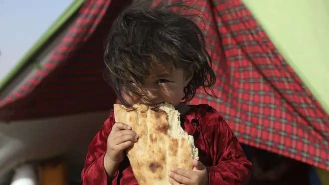 An internally displaced Afghan girl whose family fled their home due to fighting between the Taliban and Afghan security personnel, eats bread (Rahmat Gul/AP)