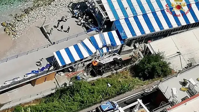 A bus lies on its side after crashing through a guardrail on Capri