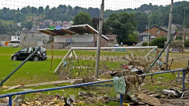 A damaged car and other debris strewn across a football pitch after flooding in Vaux-sous-Chevremont in Belgium on July 24