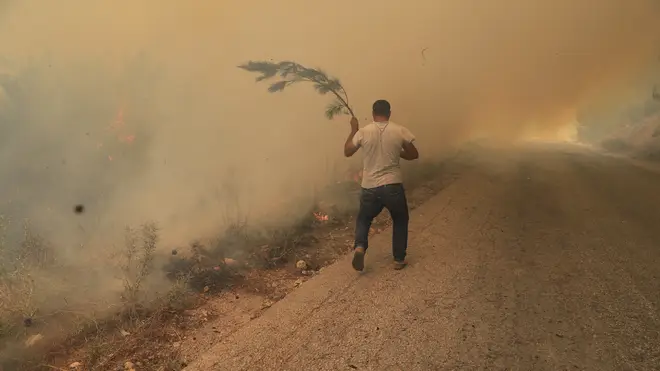 A man runs to extinguish a forest fire, at Qobayat village, in the northern Akkar province, Lebanon (Hussein Malla/AP)