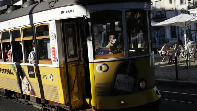 A tram conductor wearing a face mask drives through Lisbon's Graca neighbourhood