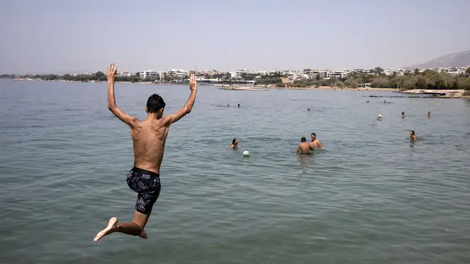 A youth jumps in the sea at a beach of Kavouri suburb, south-west of Athens