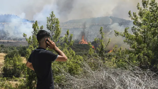 A man watches wildfires in Antalya, Turkey
