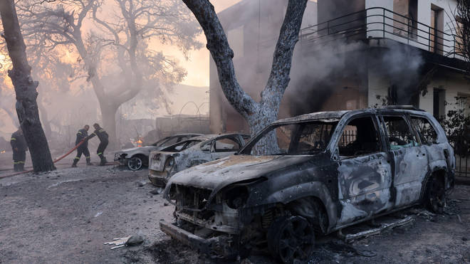 Burnt cars left as a wildfire burns in the Varympompi suburb north of Athens