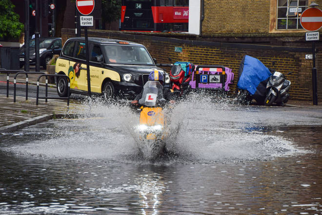 A delivery motorcyclist splashes through a flooded Farringdon Lane after a day of heavy rain in the capital.