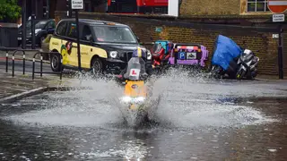 A delivery motorcyclist splashes through a flooded Farringdon Lane after a day of heavy rain in the capital.