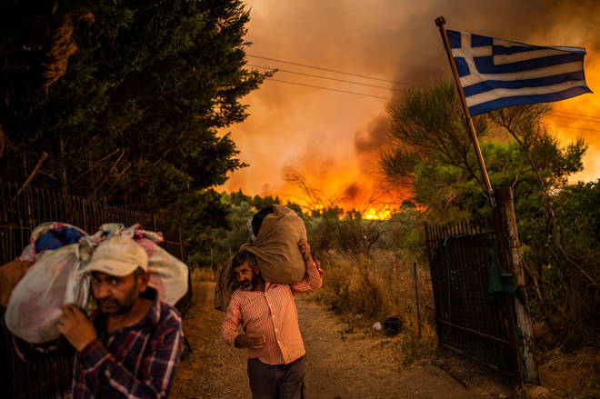 People try to move parts of their belongings to safety as a forest fire rages in a wooded area north of Athens.