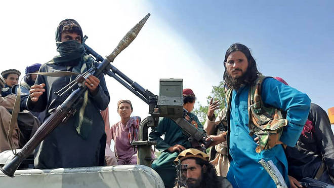 Taliban fighters sit over a vehicle on a street in Laghman province on Sunday