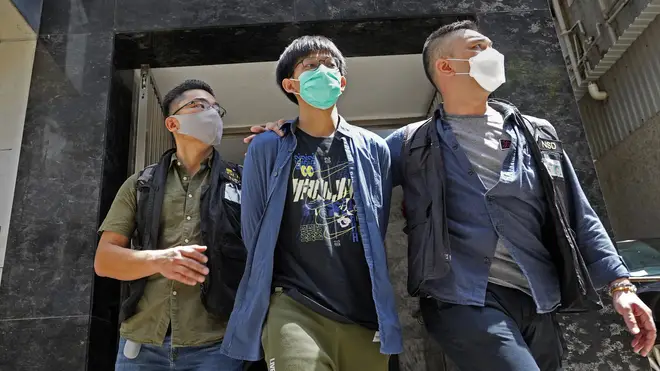 A student of Hong Kong University, centre, is escorted by police officers after a home search in Hong Kong (Vincent Yu/AP)