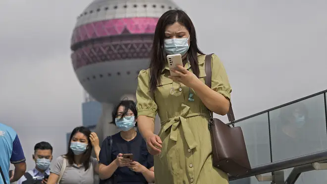 People wearing face masks using their smartphones as they walk on a bridge in Shanghai in China