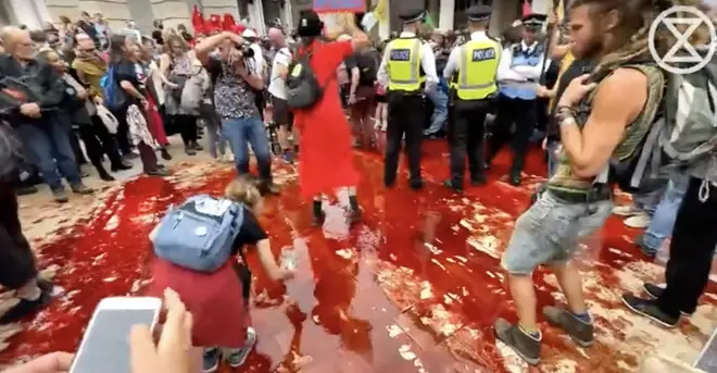 Activists spread fake blood across the ground in front of the London Stock Exchange.