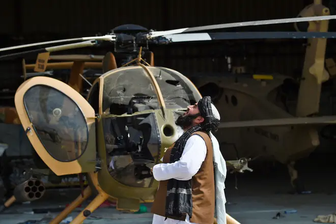 A member of the Taliban standing next to a damaged helicopter at the airport in Kabul.