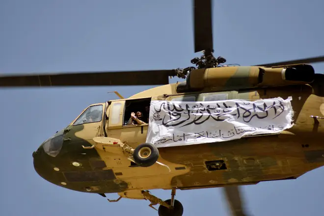 A helicopter displaying a Taliban flag flies above Taliban supporters gathered to celebrate the US withdrawal of all its troops out of Afghanistan.