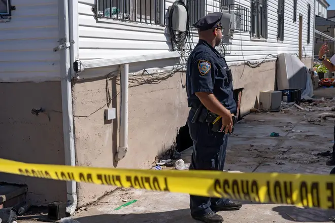 A police officer guards the house where two people died when their basement apartment in New York was flooded
