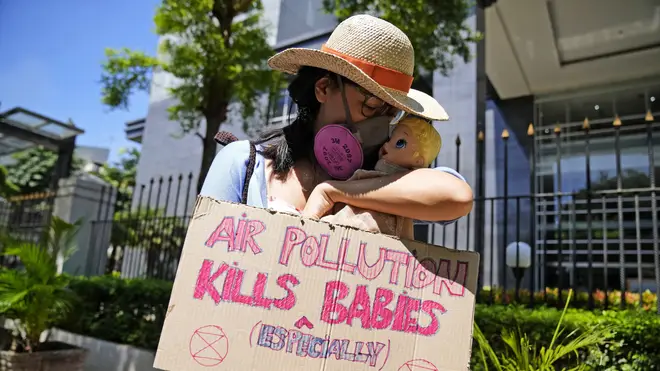 An activist displays a placard with a doll representing babies affected by air pollution during a protest outside Central Jakarta District Court