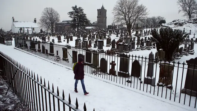 A man walks through a cemetery in the snow